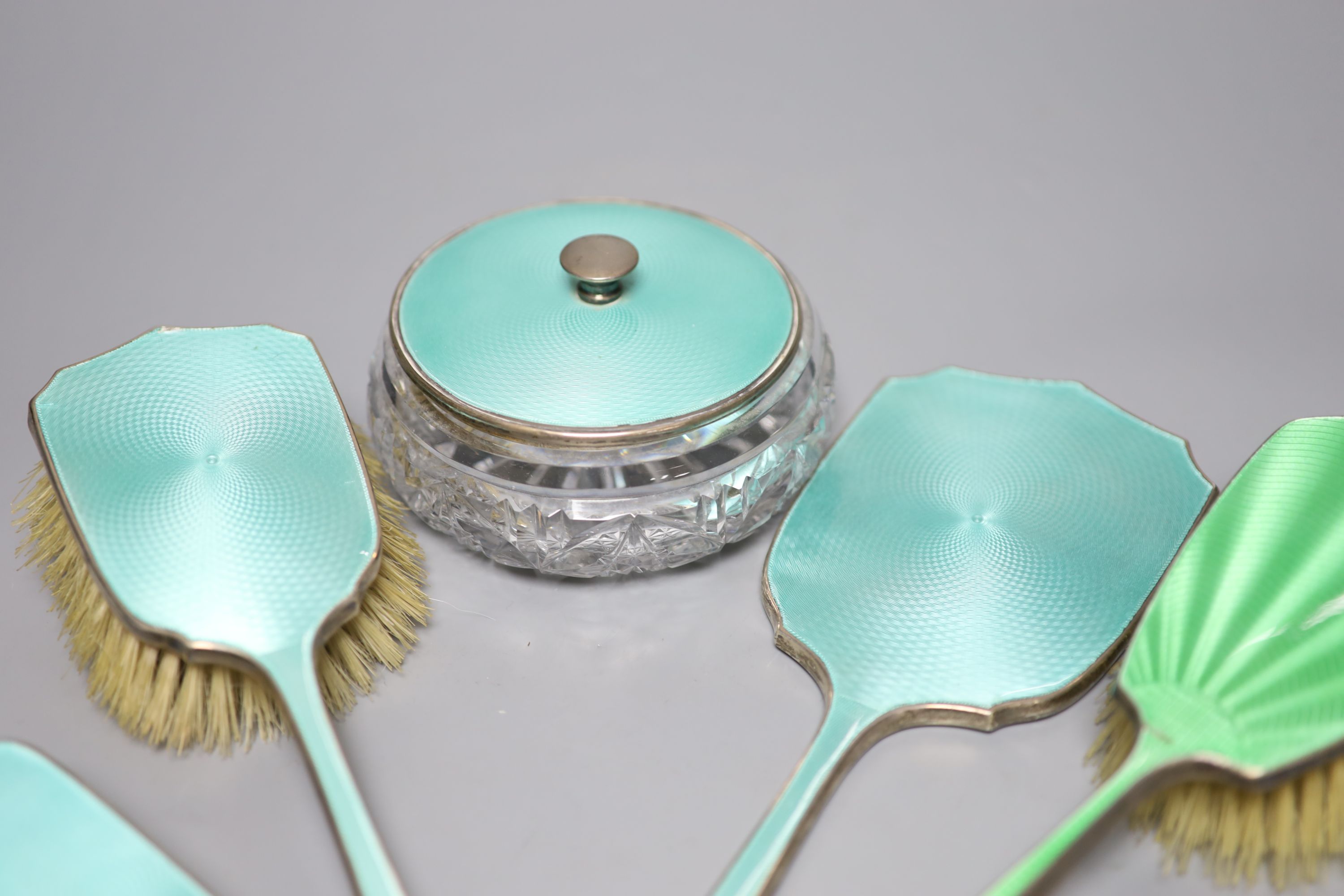 A 1930's silver and enamel toilet set including powder bowl, mirror and two brushes and one other silver & enamel brush.